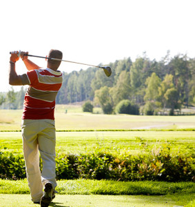 A man playing golf on a green golf course