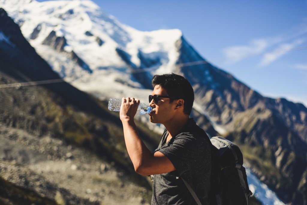 Man drinking water at the top of a mountain