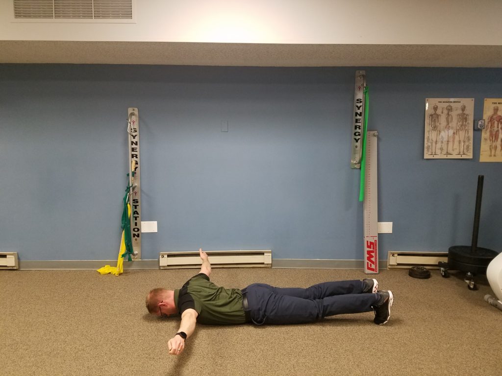 Prone YTA: Begin lying face down with toes down, knees off the floor and nose/mouth off the floor. Place your arms in a "Y", "T" or "A" position, pulse 5 times then move to another position. Perform 5 pulses in all 3 positions 5 times without resting your arms ("T" position shown). 